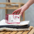 Eine Hand greift nach einer Packung OMNi-BiOTiC SKiN Intensiv-Hautbad